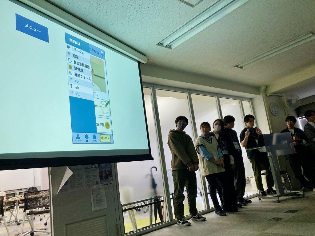 スクリーンに表示された作成したアプリのMVPを説明する男性の学生